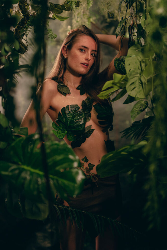 Model im künstlichen Studio-Dschungel mit aufgeklebtem Blätter Outfit