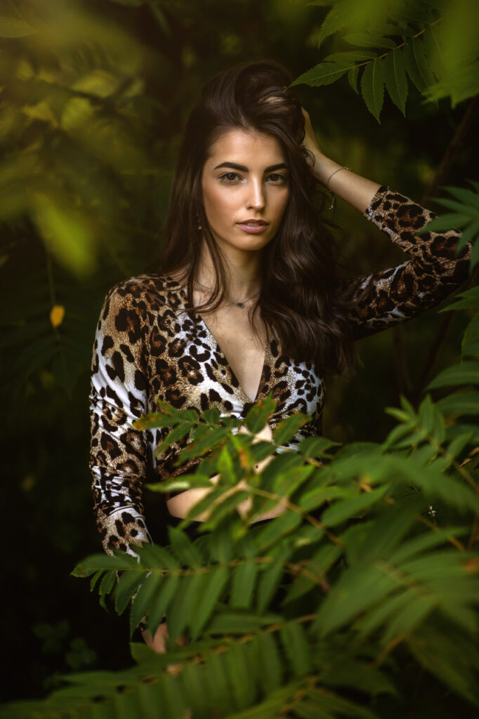 Model im Leoparden-Top umgeben von Dschungel-Blättern