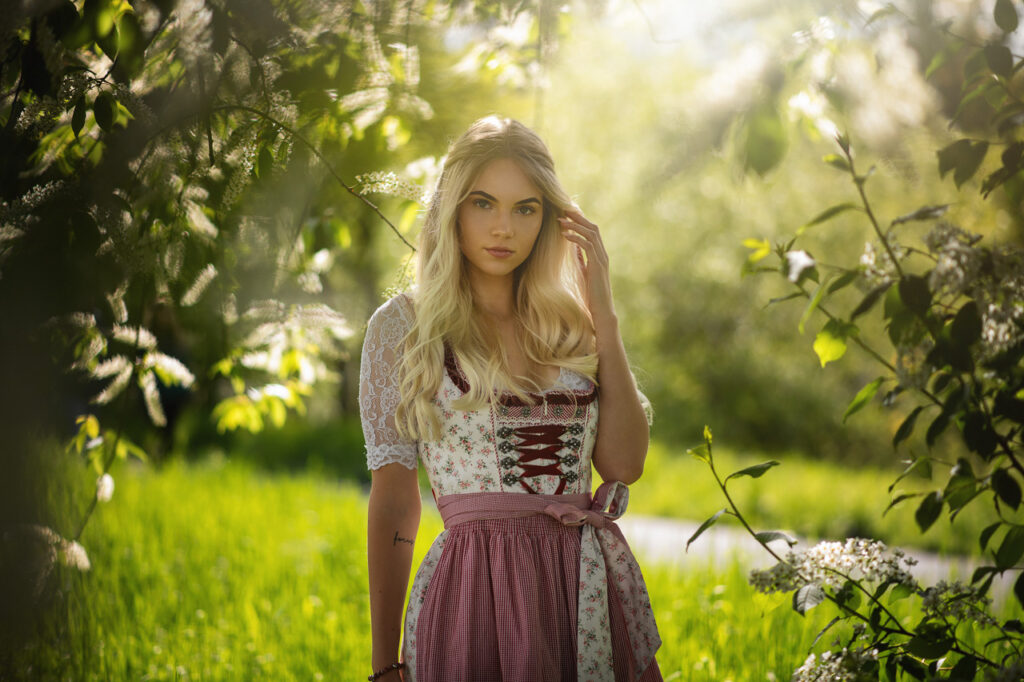 Model in traditionellem Dirndl vor grünem Hintergrund im Freien